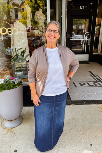Woman wearing mocha ruffled cardigan in with curved front line and long sleeves, styled layered over white top with denim skirt