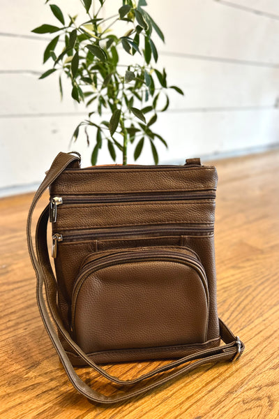 Brown leather crossbody bag with adjustable strap, multiple compartments, zippered pocket, card slots, and back phone pocket.