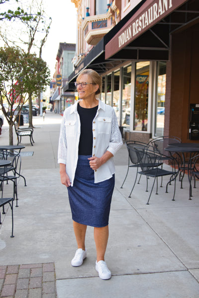 Woman wearing denim-look knit midi skirt with comfort waistband and modified pencil fit, styled with a black tee and white jacket