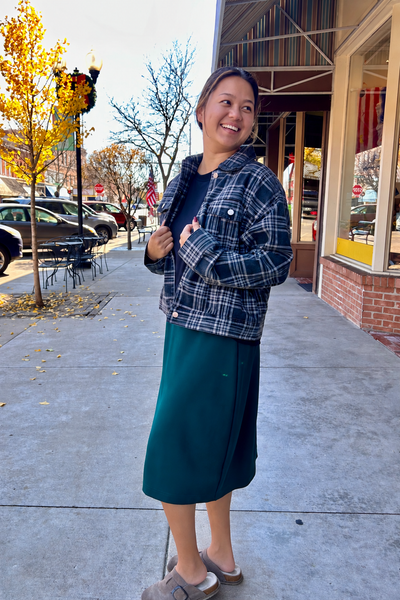Women's charcoal gray plaid denim jacket with button-front closure, chest pockets, and relaxed fit, styled with a green midi skirt.