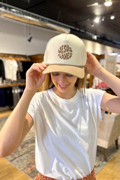Neutral ash mocha baseball hat with embroidered “Jesus Saves” lettering styled with casual modest clothing for everyday faith-inspired fashion.