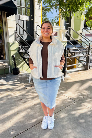 Woman on sidewalk wearing cozy snap up sherpa vest with bow ties on the side for great fit. 