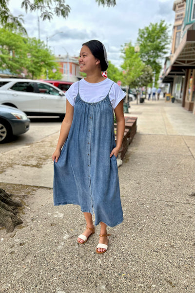 Woman in a blue dress standing on a sidewalk with a city street background