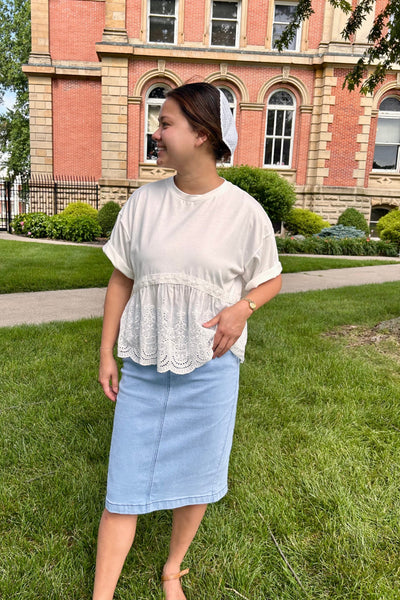 Woman wearing a modest flowing white top and denim skirt standing on the Courthouse lawn. 