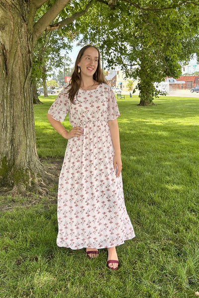 Woman wearing a modest floral maxi dress standing in the grass on the courthouse lawn.