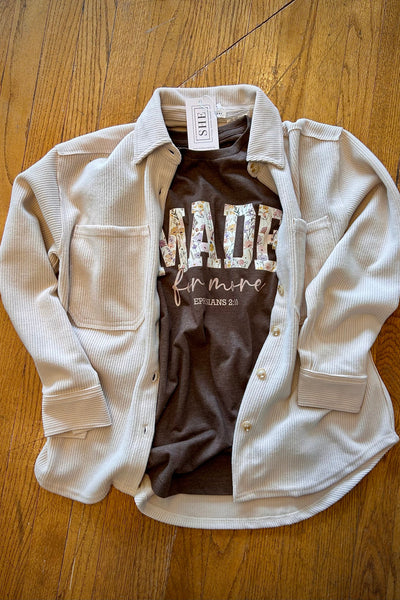 White jacket with a brown shirt underneath on a wooden surface