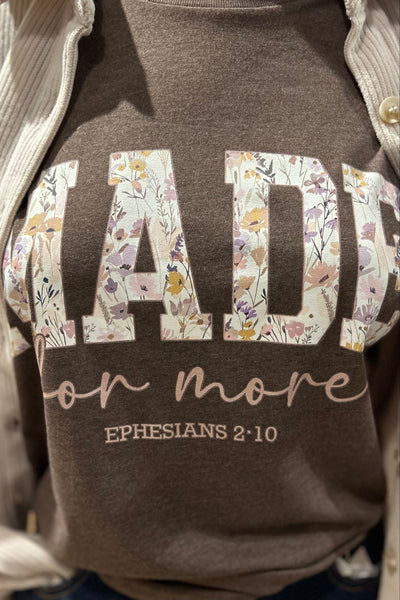 Brown shirt with floral text design and Bible verse on a person wearing a light-colored jacket.