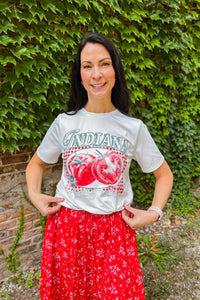 Woman wearing white Indiana  graphic tee with vintage “100% organic fresh tomatoes” print. Styled with a red skirt