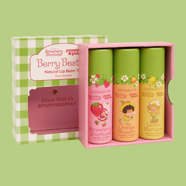 A boxed set of three lip balm tubes displayed in front of the product box on a solid light green background. The set is branded Poppy & Pout! and named Berry Best.